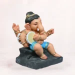 Side angle view of Cow Bal Sky Blue Dhoti 20 Inch Eco-Friendly Clay Ganpati Idol leaning on a painted cow figure