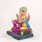 Side angle view of Koach Load Purple 18 Inch Eco-Friendly Clay Ganpati Idol sitting on a traditional purple load bolster